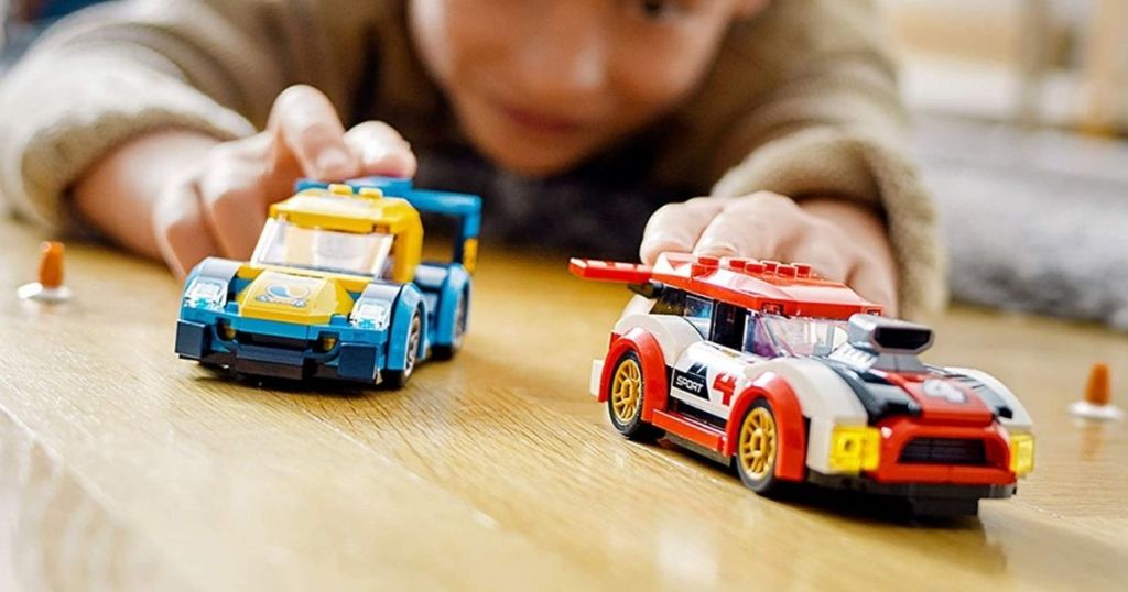 boy playing with two LEGO cars