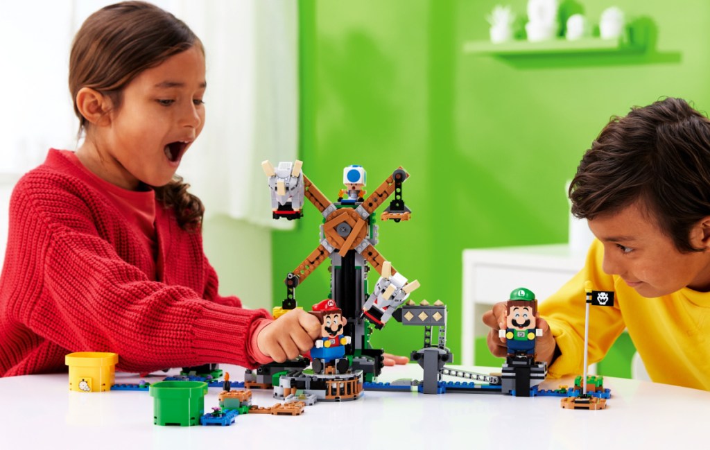 two kids playing with a LEGO Super Mario Reznor Knockdown Expansion Set