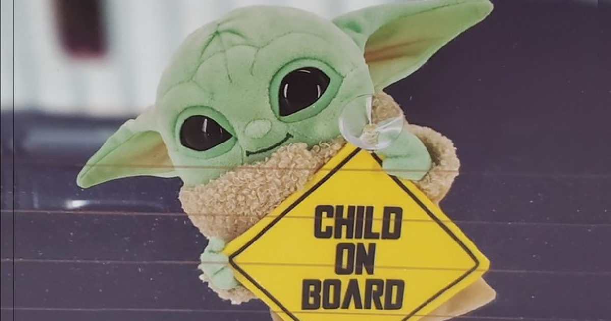 plush Mandalorian holding child on Board sign