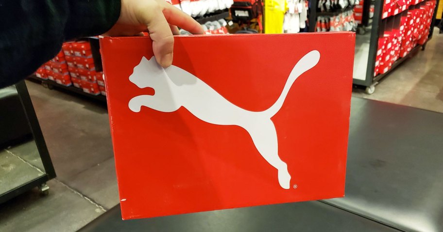 person holding up a red puma shoe box