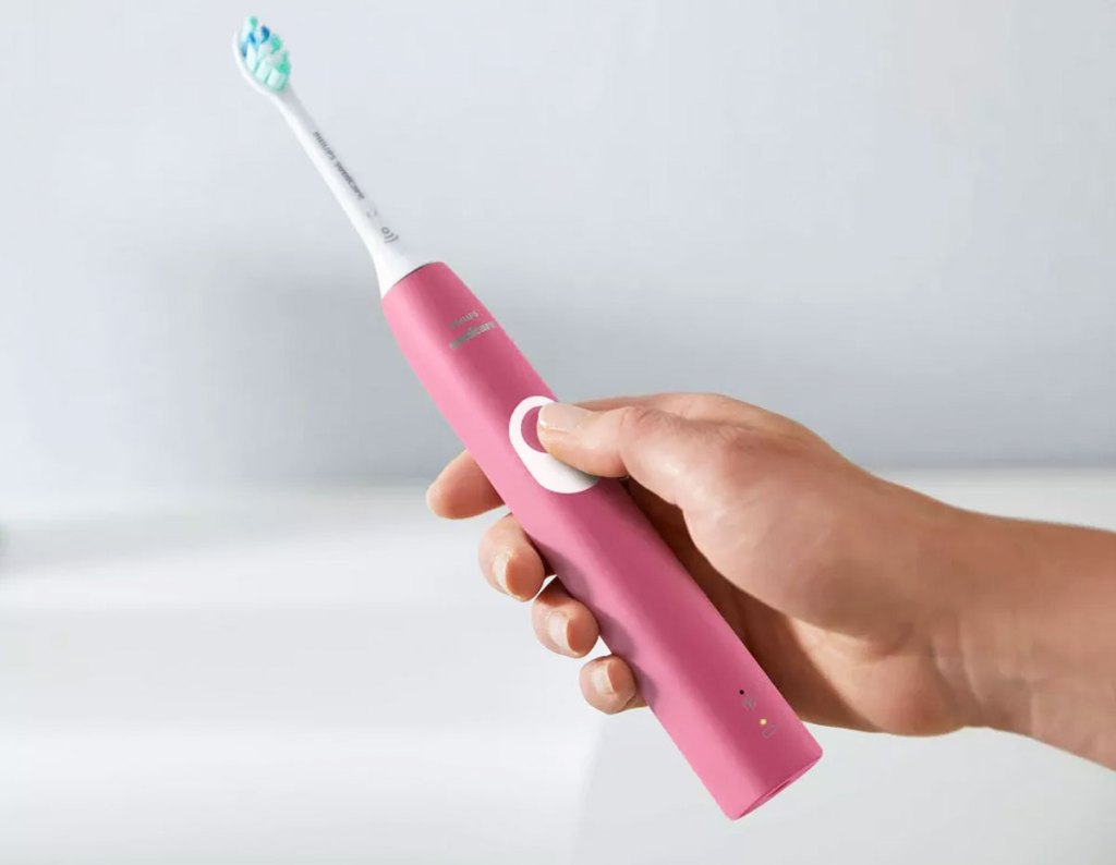 hand holding a pink electric toothbrush