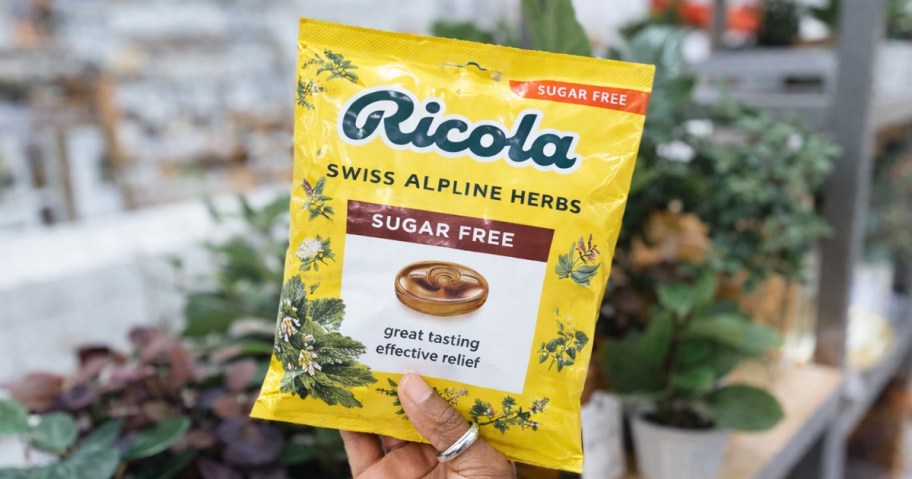 hand holding up a yellow bag of Ricola Sugar-Free Cough Drops in store