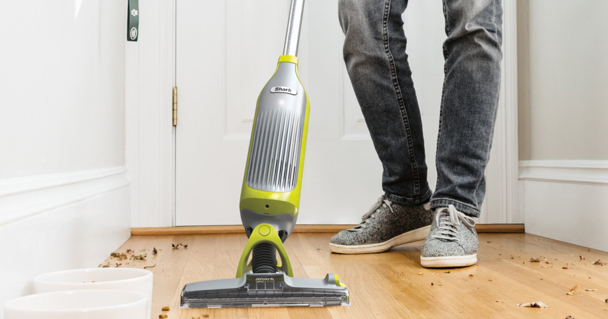 person in jeans using a Shark VacMop to clean a wood floor