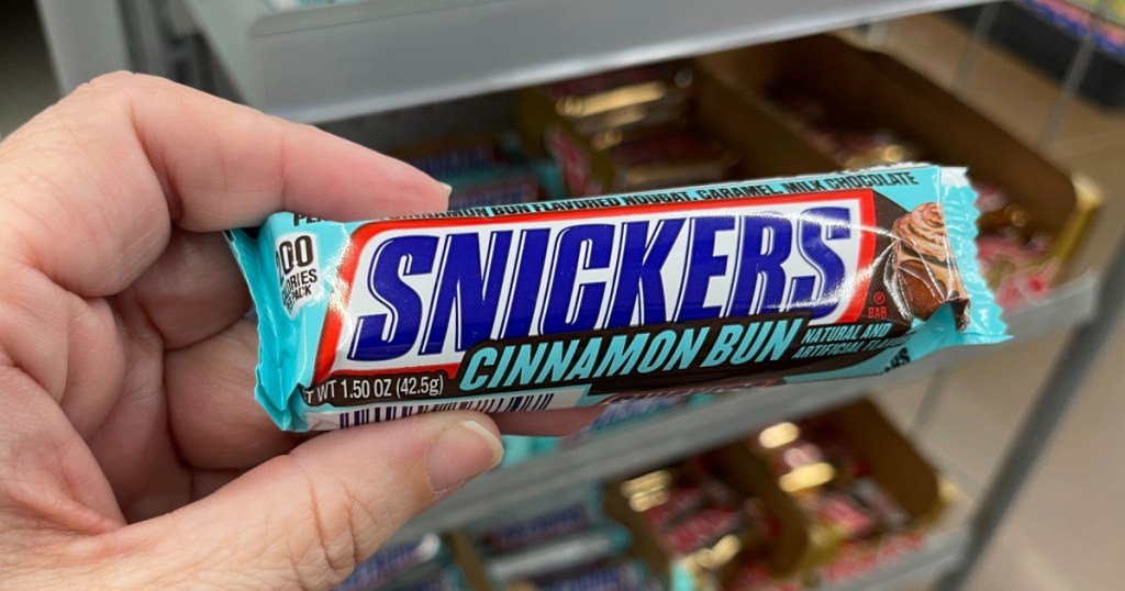 woman holding snickers cinnamon bun candy bar