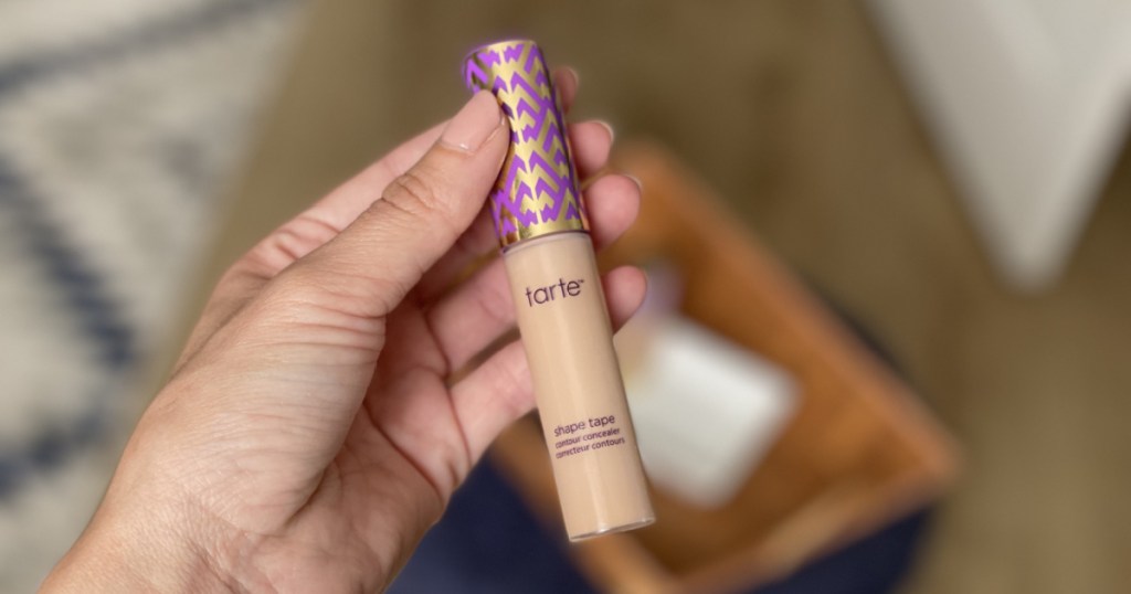 manicured hand holding beauty concealer