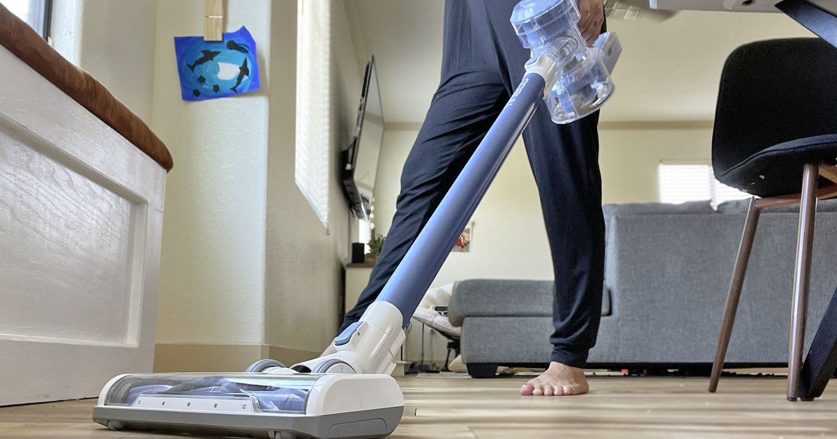 woman using blue and white stick vacuum