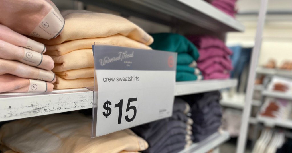 sweaters on shelf with sign in front 