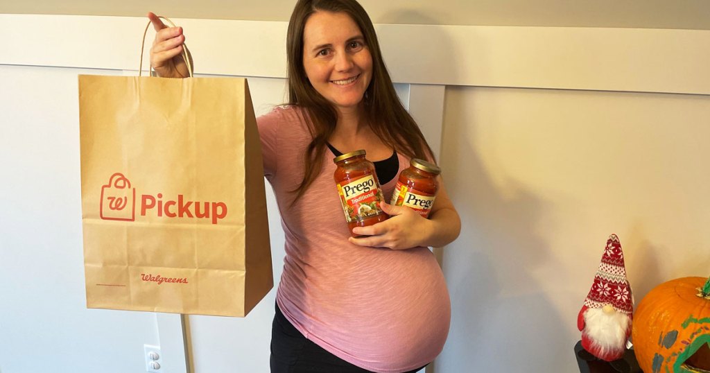 pregnant woman holding up prego pasta sauces and walgreens bag