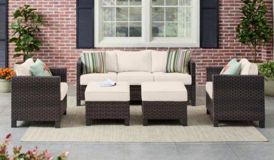 Dark brown wicker patio set with almond colored cushions outside in front of red brick house