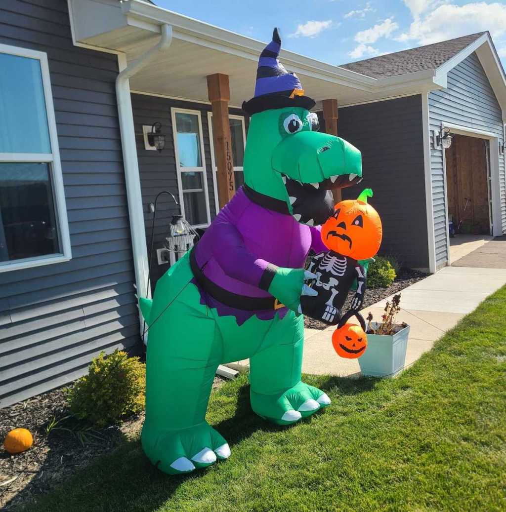 halloween dinosaur holding pumpkin in front yard