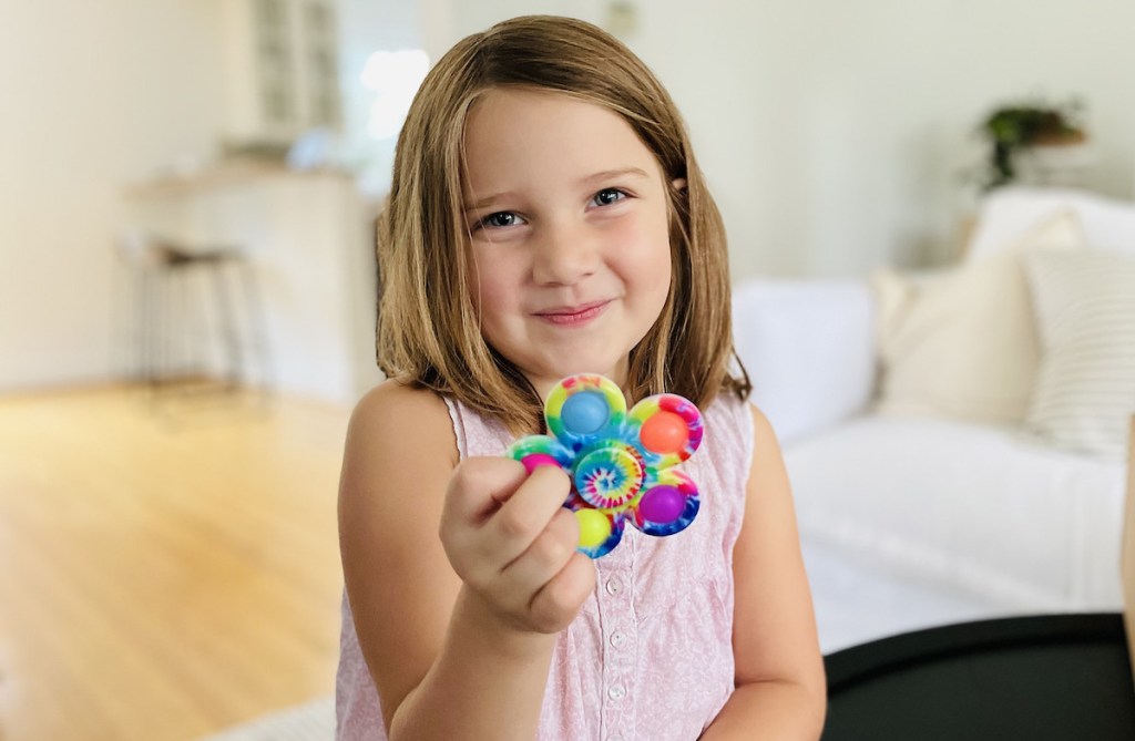 girl holding tie dye fidget toy spinner smiling