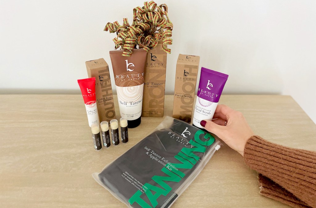 hand holding beauty by earth facial scrub with other beauty products on table