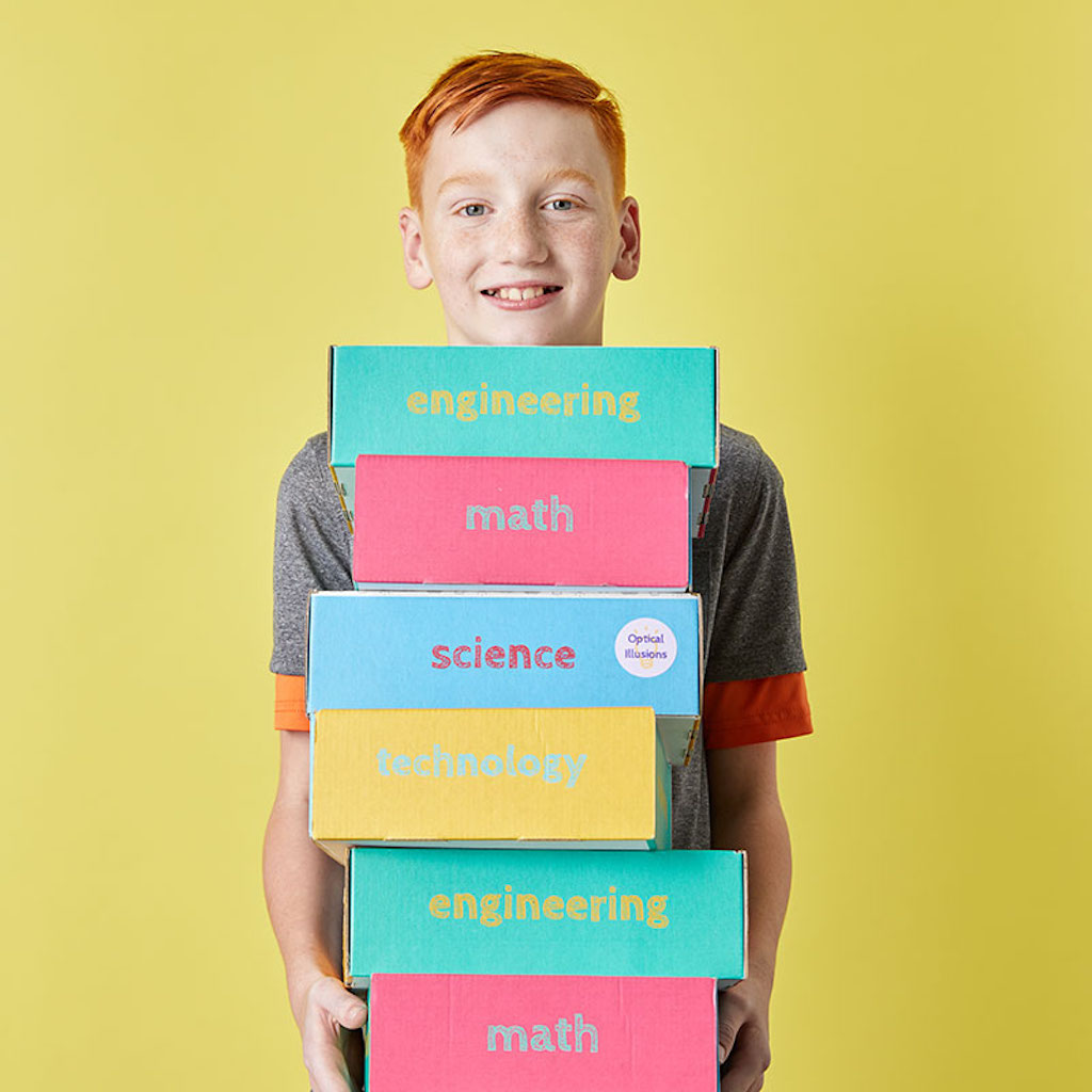 boy holding several Annie’s Genius Boxes