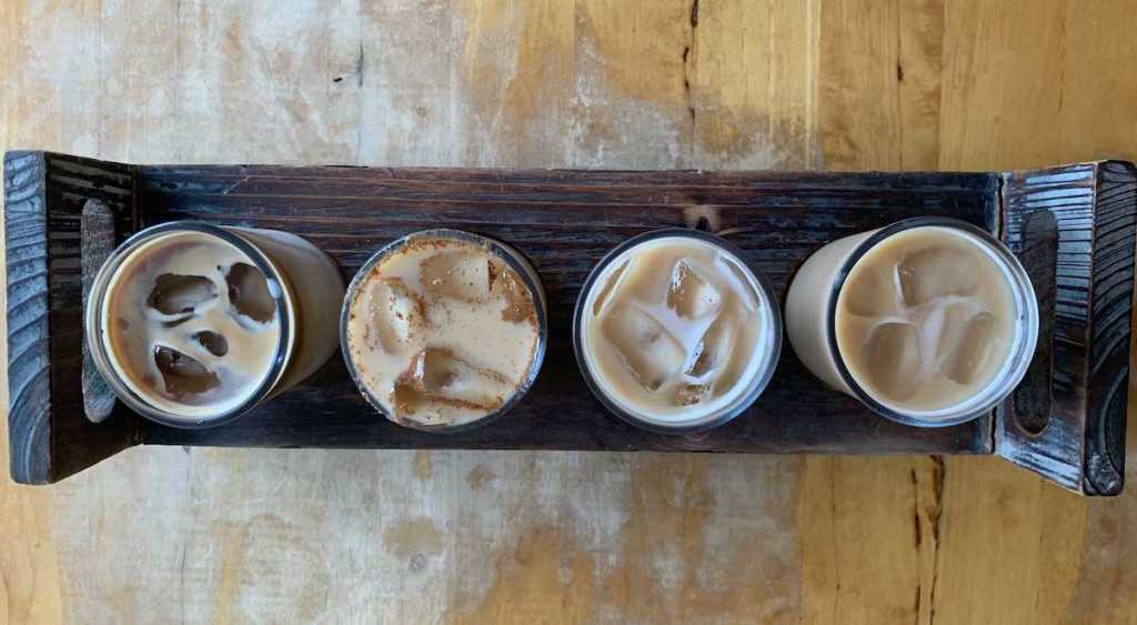 row of various iced coffees in glasses on wood coffee flight