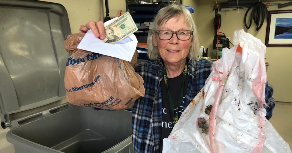 woman holding up trash bags and money in envelope 