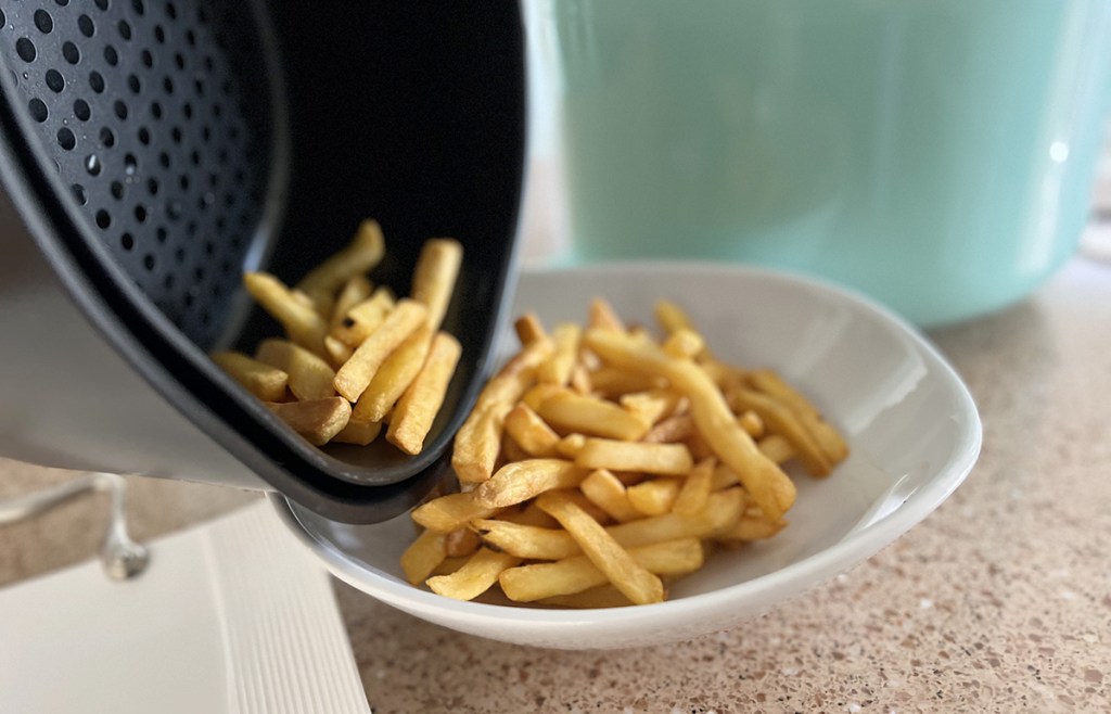 pouring fries from dash air fryer onto plate