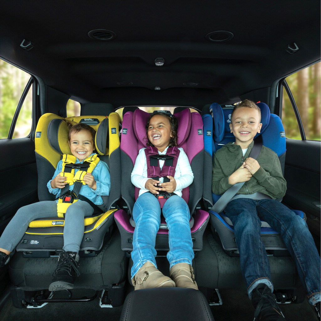 three Diono car seats in car with kids buckled in each one 