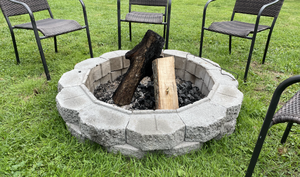 round firepit in grass with chairs
