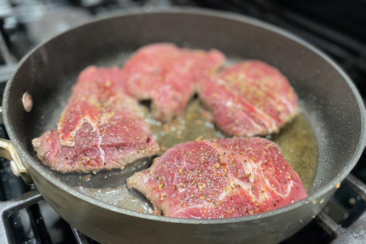 flat iron steaks cooking in pan