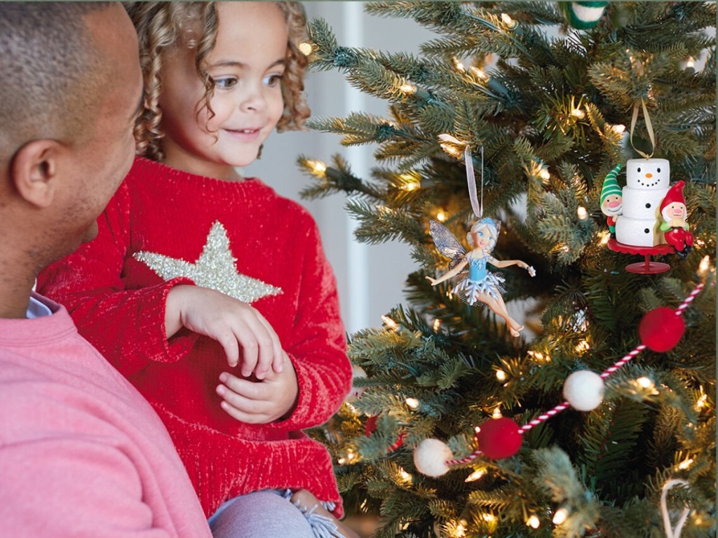 man holding child up to Christmas tree