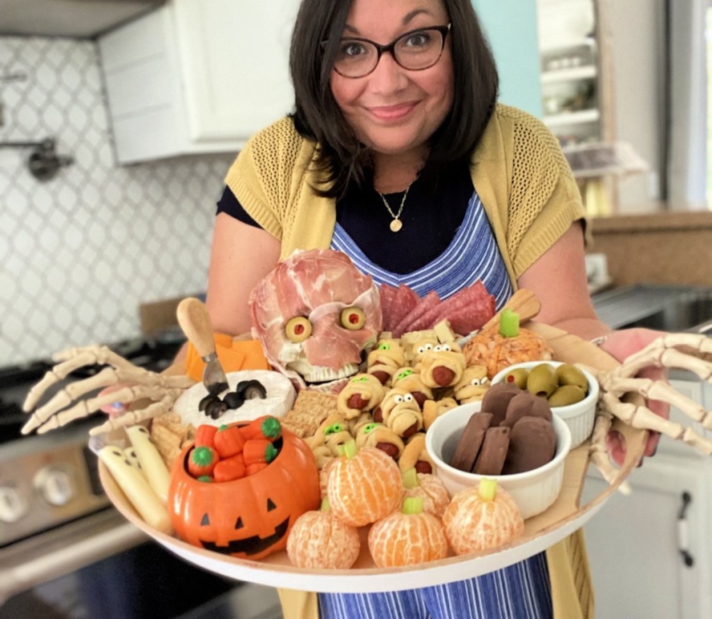 woman holding a halloween themed charcuterie board with food