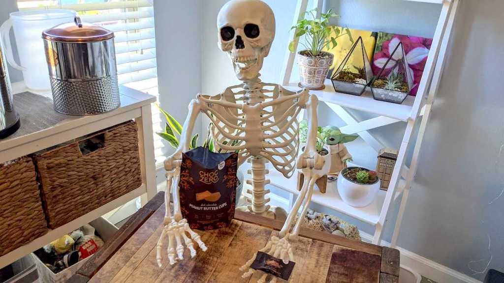 skeleton posed with keto choczero chocolates on table