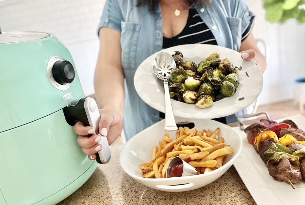 woman with dash air dryer, fries, and brussels sprouts