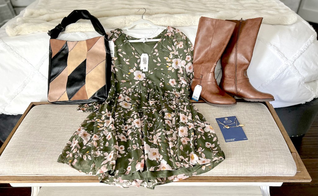 purse floral dress brown boots and necklace laying on bench in bedroom