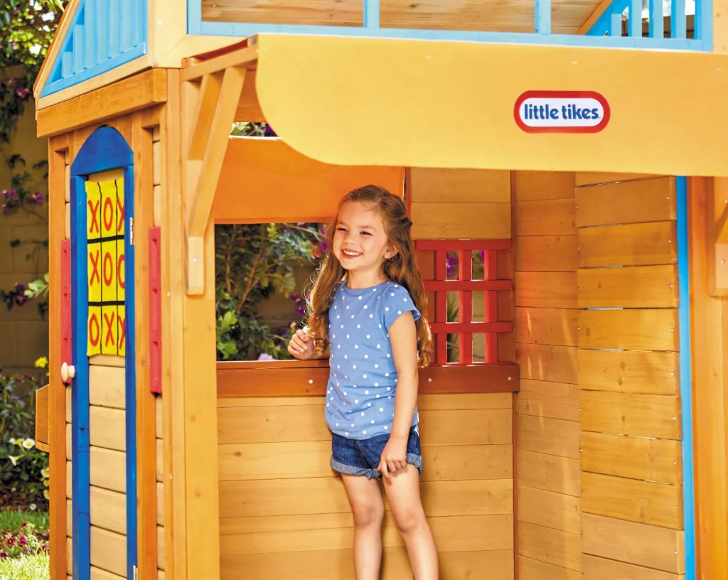 young girl standing inside a wooden play house
