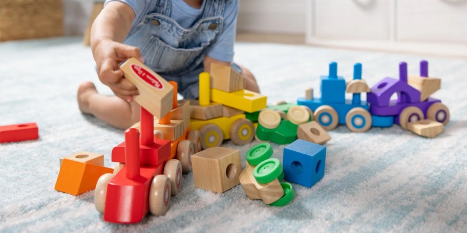 boy playing with wooden melissa doug train set