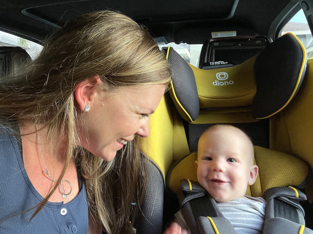 mom smiling at baby who's sitting in diono car seat 