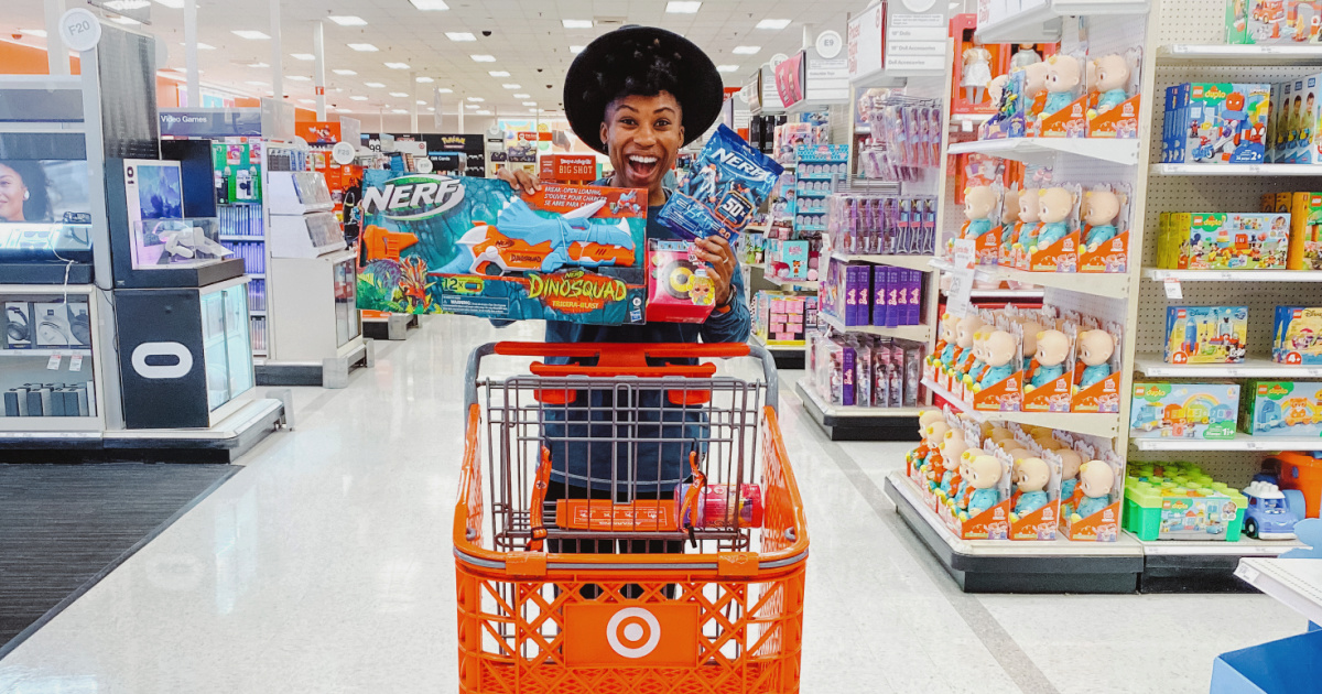 woman holding an arm full of nerf and lol surprise toys behind a target cart in store