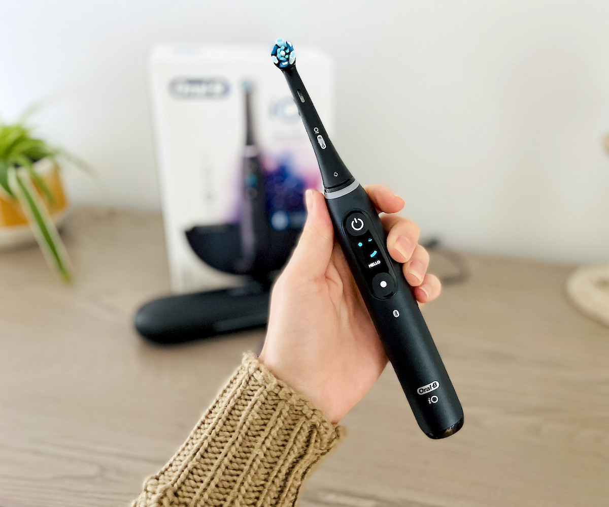 hand holding black oral b electric toothbrush