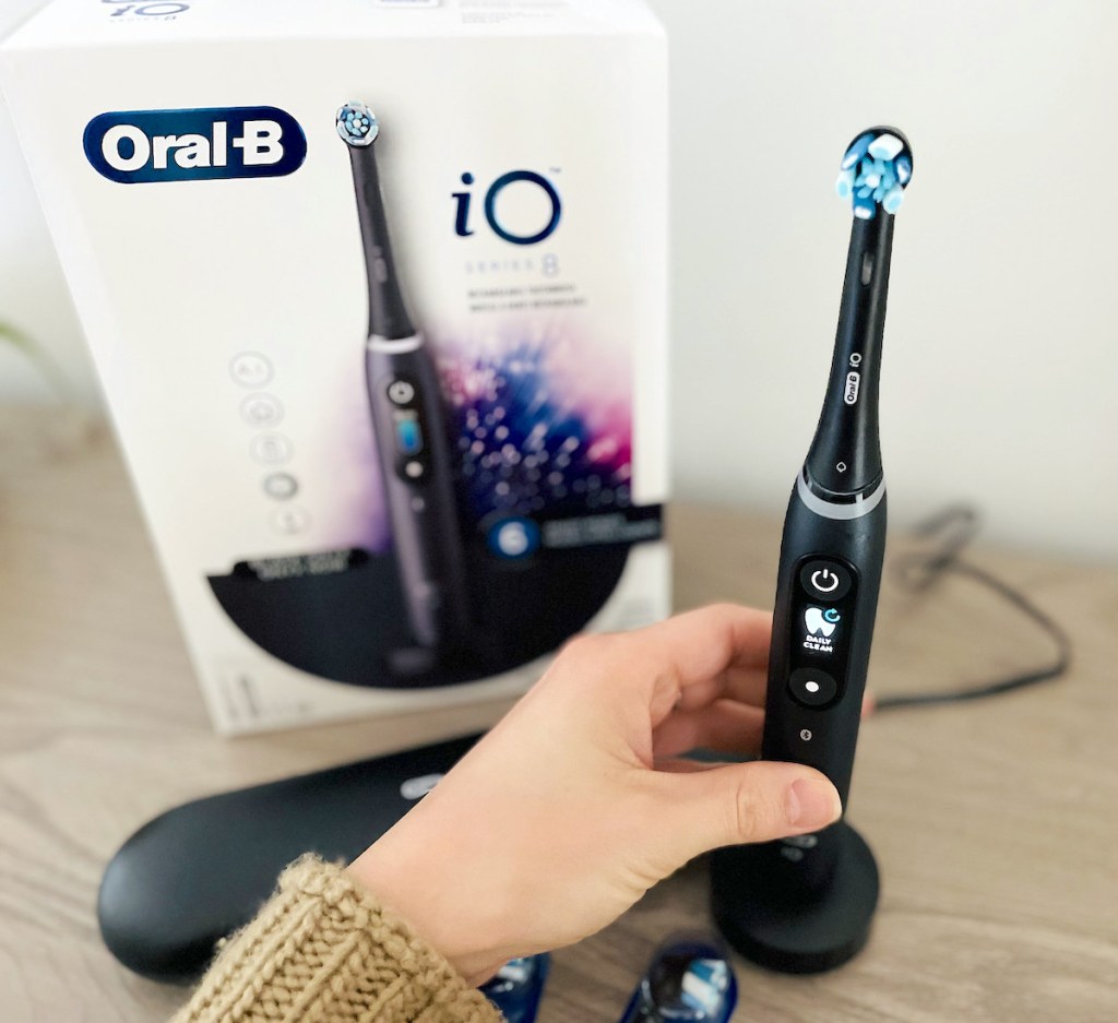 close up of hand holding black oral b electric toothbrush