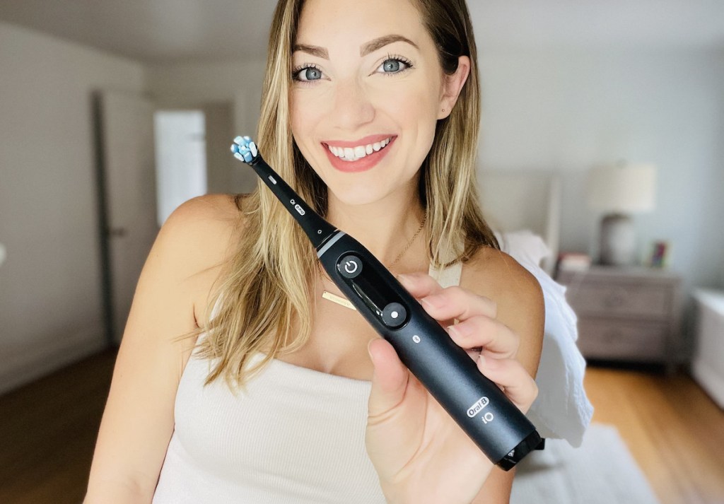 woman holding black electric toothbrush