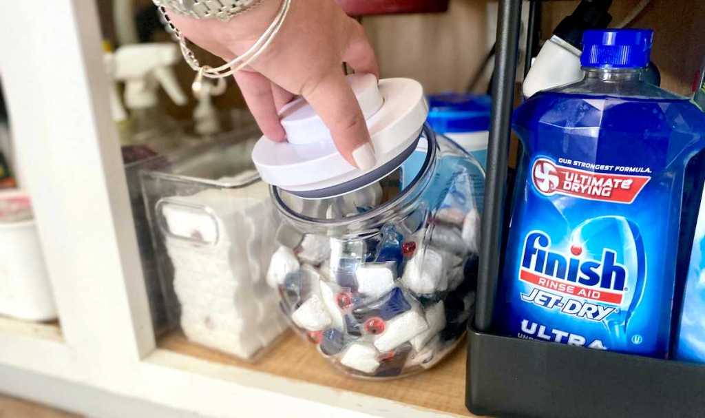 hand opening clear storage container with laundry pods inside