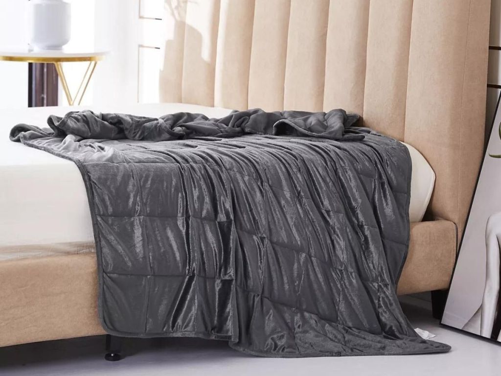 gray plush weighted blanket draped across bed