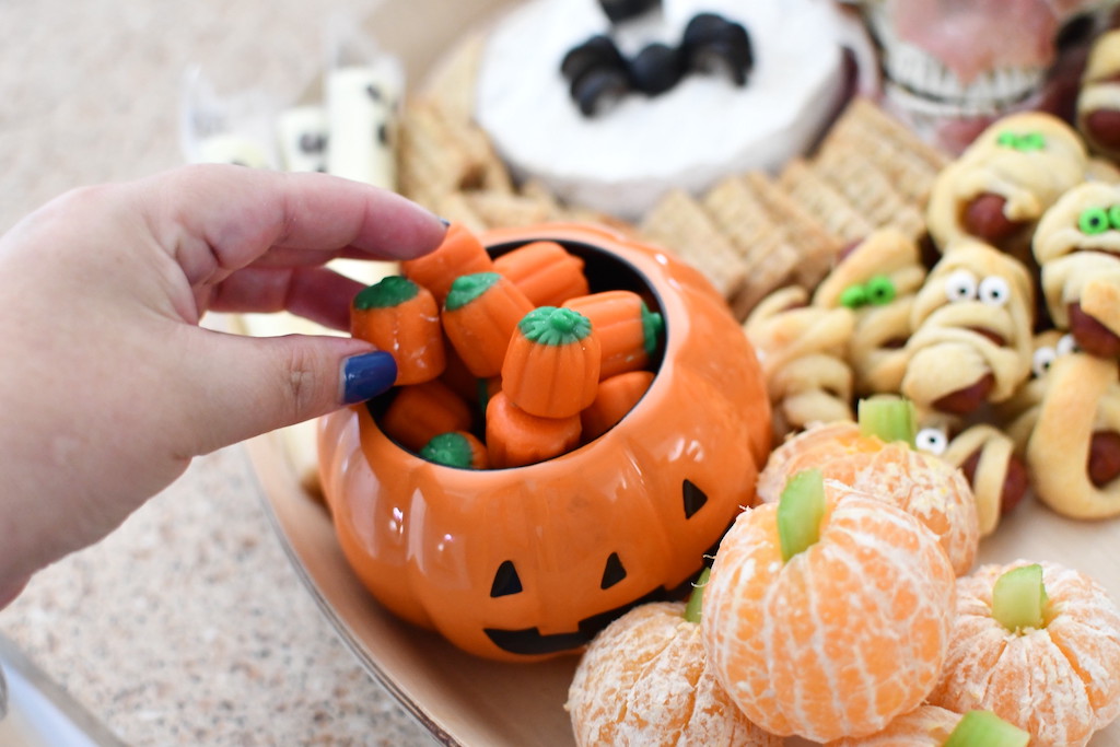 pulling out a pumpkin candy from Halloween snack board