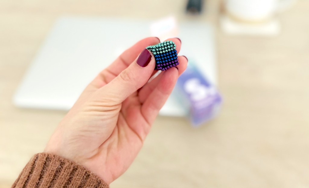 hand holding cube of colored magnetic balls