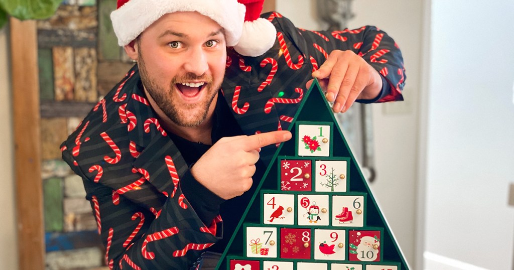 man wearing christmas jacket pointing to advent calendar