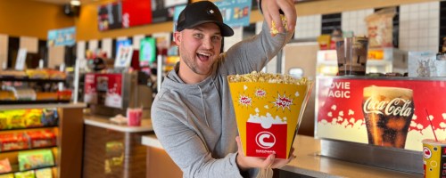 man holding a bag of popcorn in a movie theater
