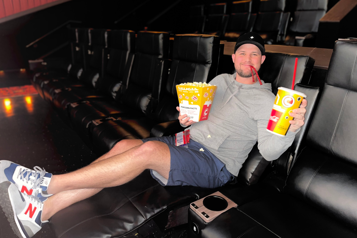 man with popcorn sitting in movie theater seats