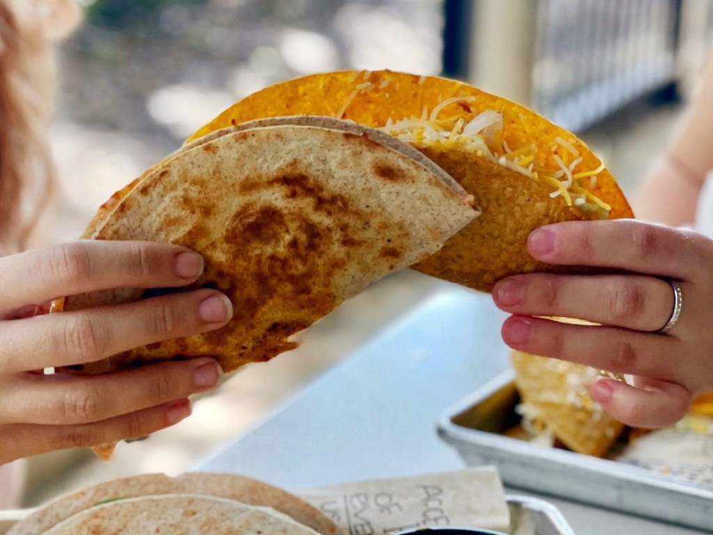 two hands holding tacos