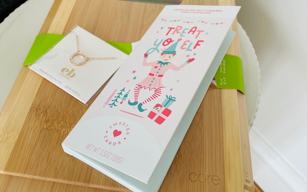 holiday chocolate card sitting on top of wooden cutting boards next to gold necklace