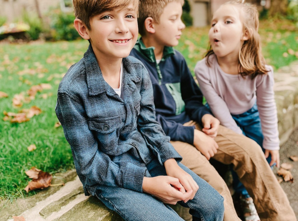 close up of boys smiling on stone wall with kids