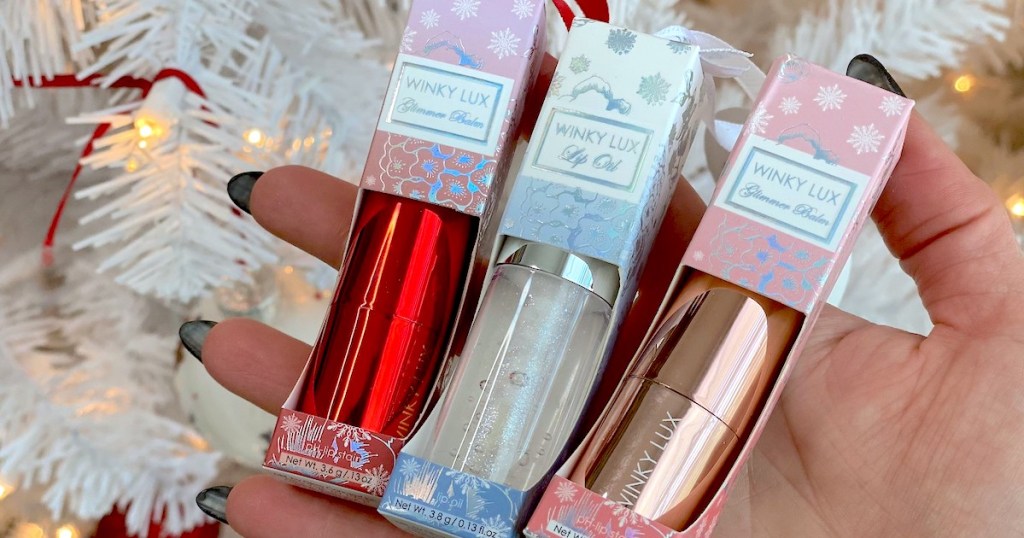 hand holding three different kinds of winky lux lip products
