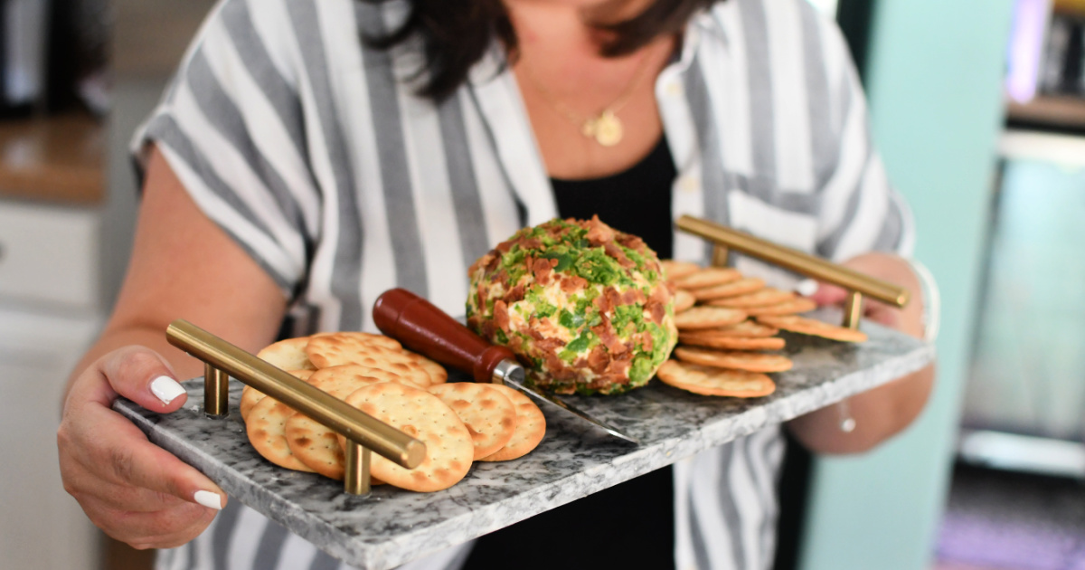 woman holding a tray with bacon jalapeno cheeseball 