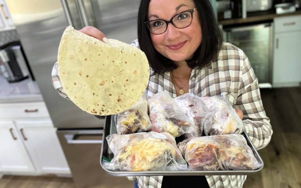 woman holding a tray of frozen breakfast burrito pouches