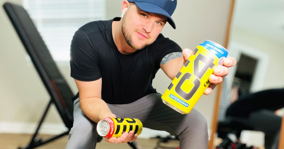 man holding 2 cans of energy drinks