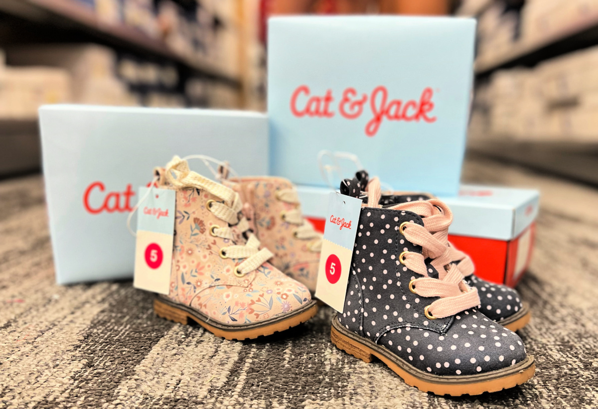 two pairs of cat and jack boots on a store floor with cat and jack boxes stacked behind them
